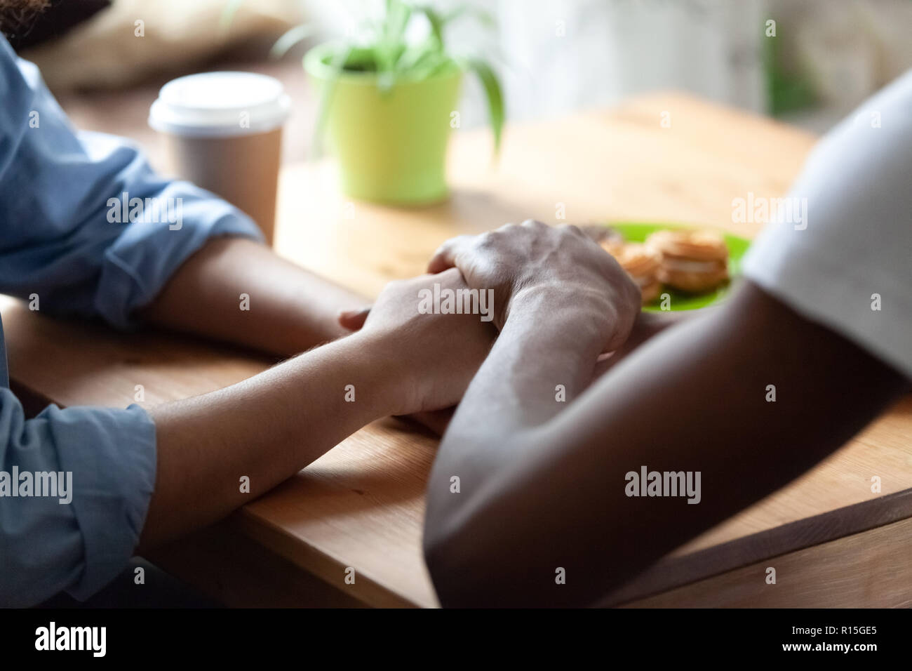 Africano nero guy mantiene la mano della ragazza amata, seduti insieme a tavola che esprime mostrando il suo sincero sentimento o importante scusarsi dicendo dispiace. Affidabile Foto Stock