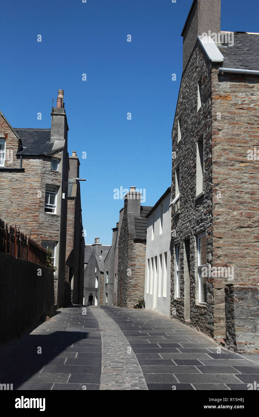 Vecchie case di pietra arenaria in Stromness, Orkney con pietre per pavimentazione da una cava locale e ciottoli nel centro della strada. Foto Stock