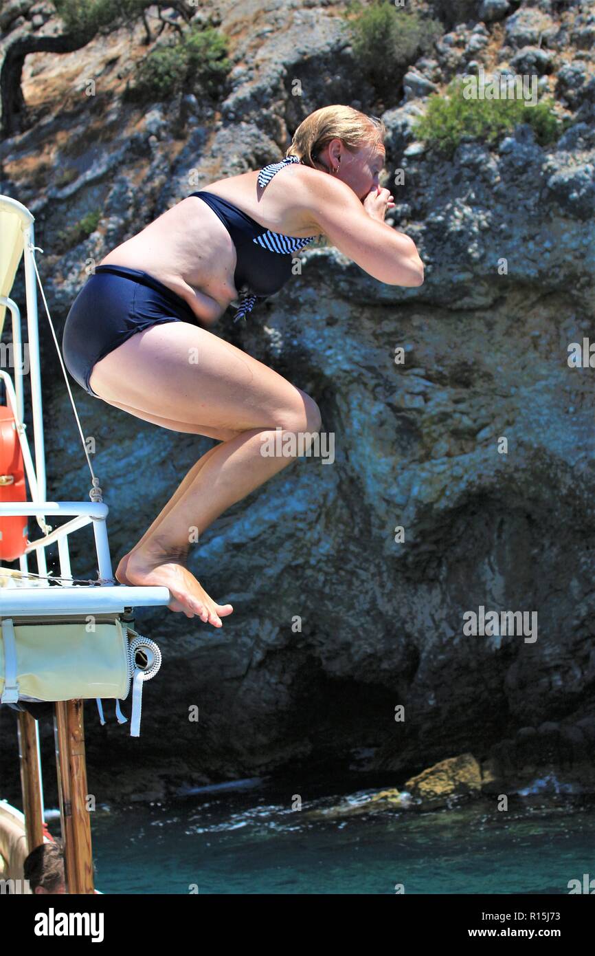Femmina caucasica salti turistico/immersioni fuori da una barca in acqua a Dalyan, Turchia. Foto Stock