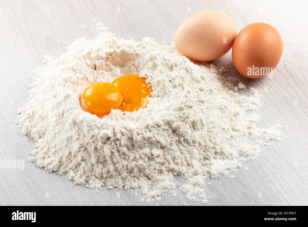 Pila di farina con i tuorli d'uovo per la pasta sul tavolo Foto Stock