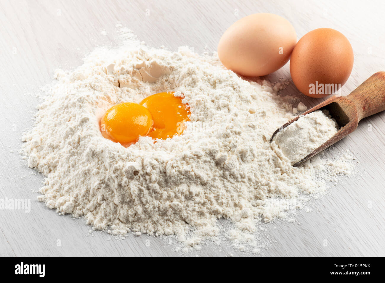 Pila di farina con i tuorli d'uovo per la pasta sul tavolo Foto Stock