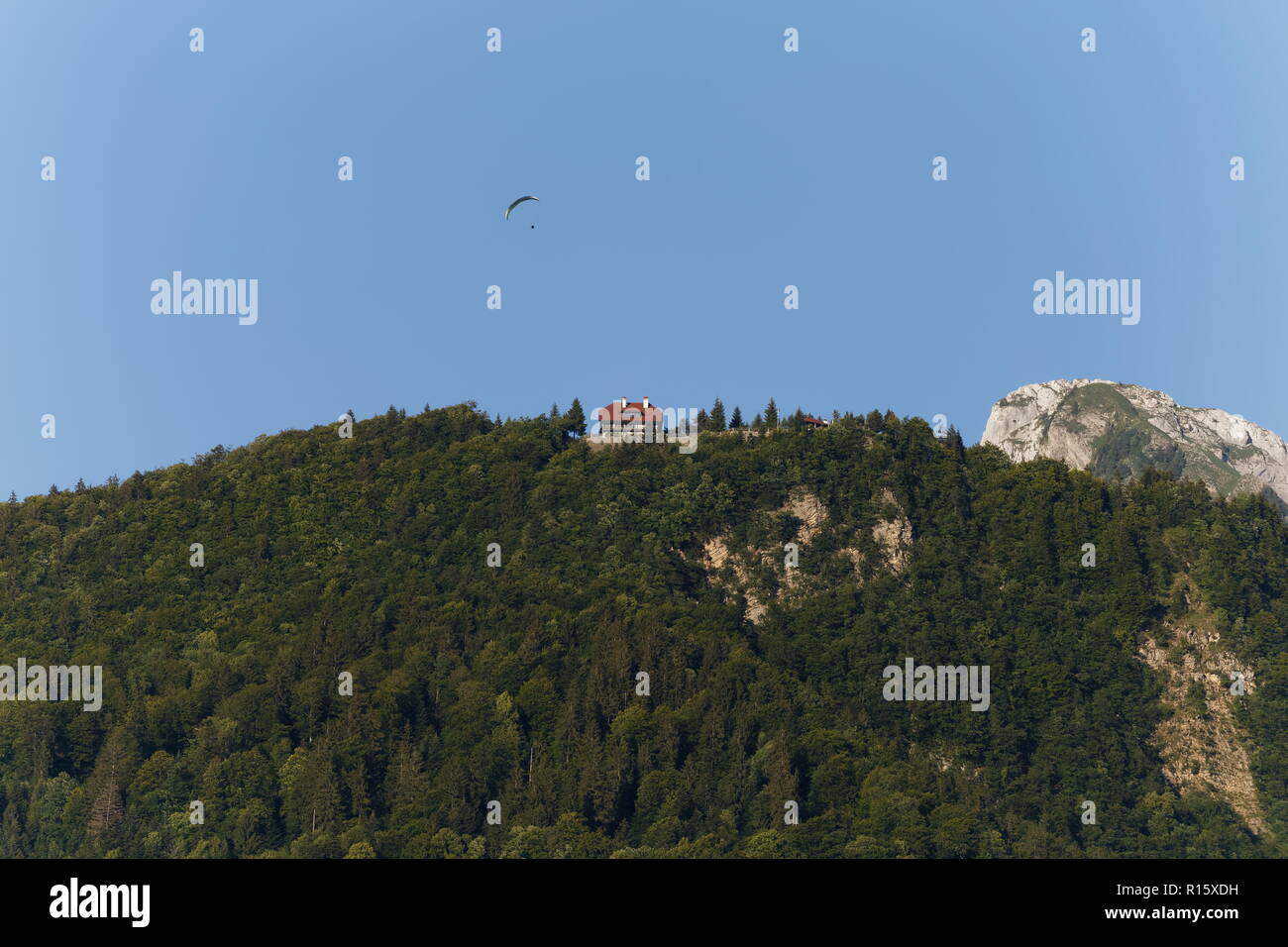 Parapendio volare al di sopra di una casa sulla cima della montagna sopra il lago di Annecy Francia Foto Stock