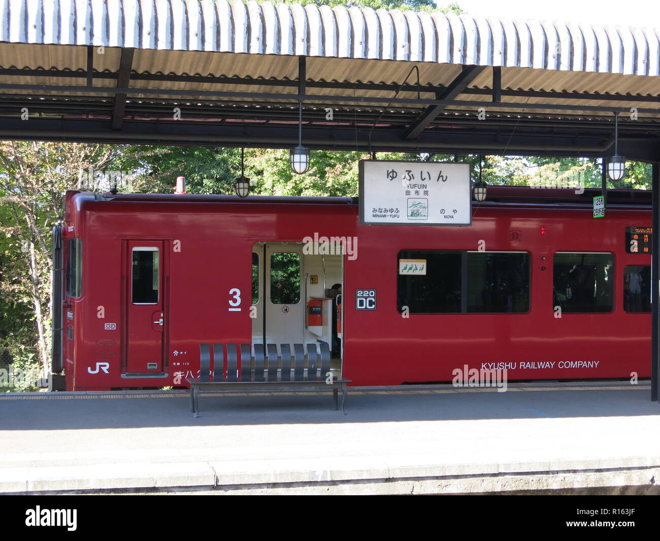 Un trenino rosso di proprietà di Kyushu Azienda ferroviaria è in attesa sulla piattaforma A Yufuin stazione ferroviaria prima della partenza Foto Stock