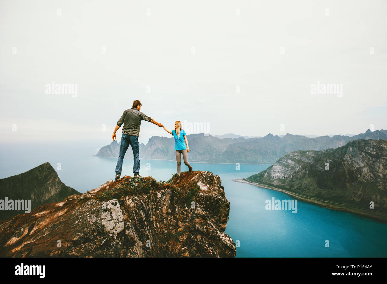 Viaggiare giovane mani tenendo insieme sul bordo scogliera in Norvegia un uomo e una donna famiglia uno stile di vita sano vacanze estive outdoor amici emozioni felici Foto Stock