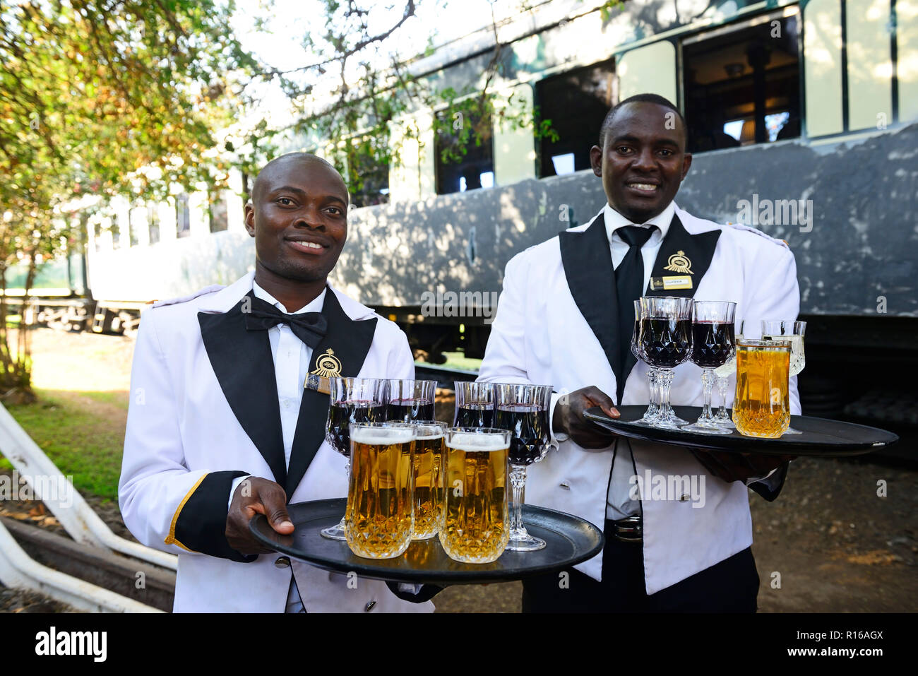 Il personale di servizio con drink di benvenuto nella parte anteriore del treno di lusso, Royal Livingstone Express, Livingstone, Zambia Foto Stock