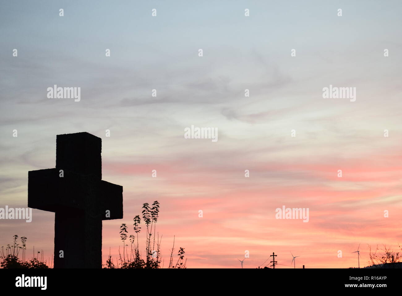 Time-lapse del sole al tramonto di sera Cielo di tramonto visto da dietro una pietra arenaria rossa croce durante l'impostazione di Sun nel cimitero civile Reimsbach Foto Stock