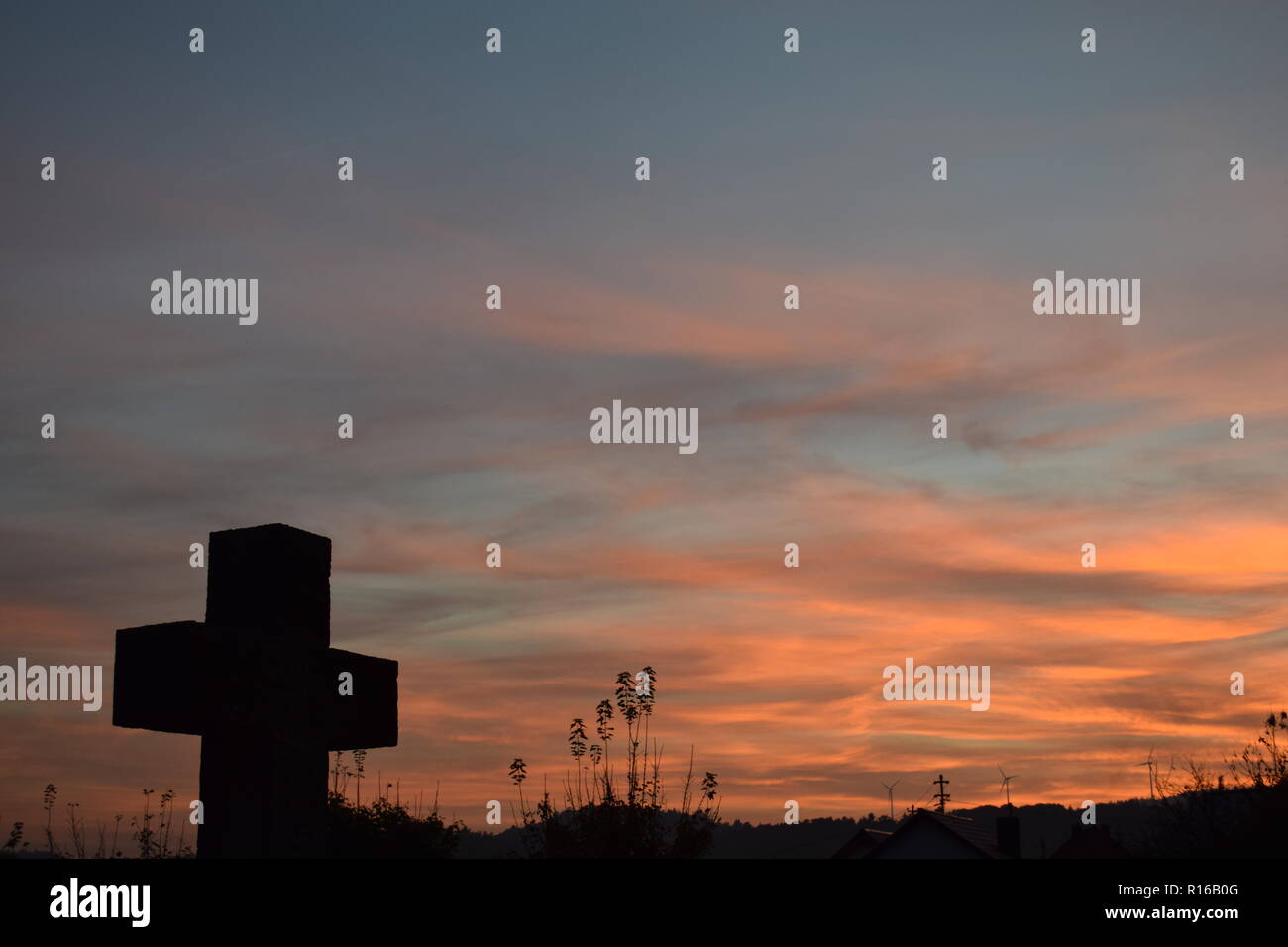 Time-lapse del sole al tramonto di sera Cielo di tramonto visto da dietro una pietra arenaria rossa croce durante l'impostazione di Sun nel cimitero civile Reimsbach Foto Stock