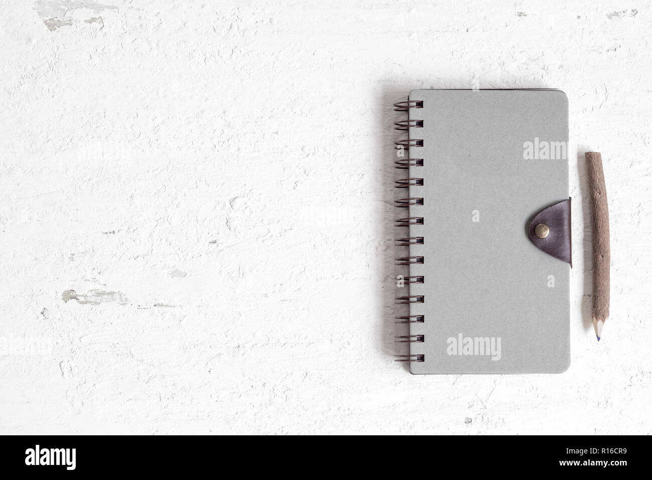 Piatto di laici notebook chiuso con coperchio bianco su bianco arrugginito un tavolo di legno. Vista da sopra con copia spazio per il modello di pagina di intestazione e mockup. Foto Stock