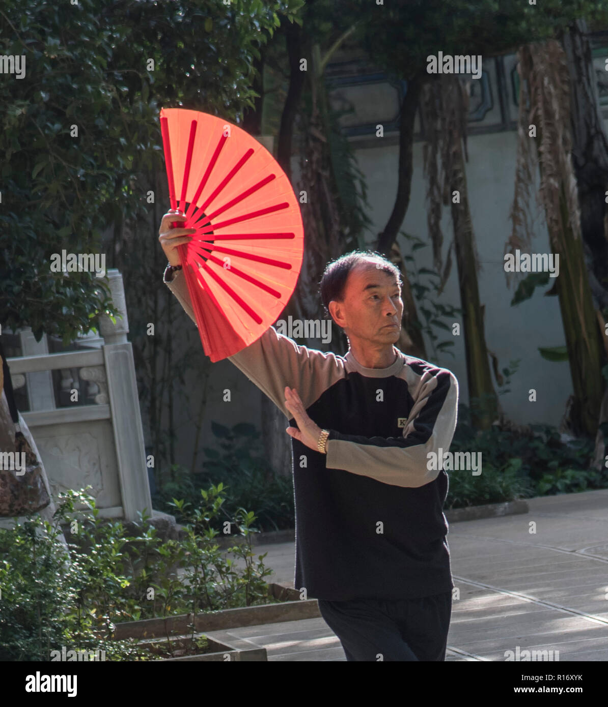 gentleman cinese che esegue la routine di danza in un parco locale con un ventilatore rosso. Cina Foto Stock