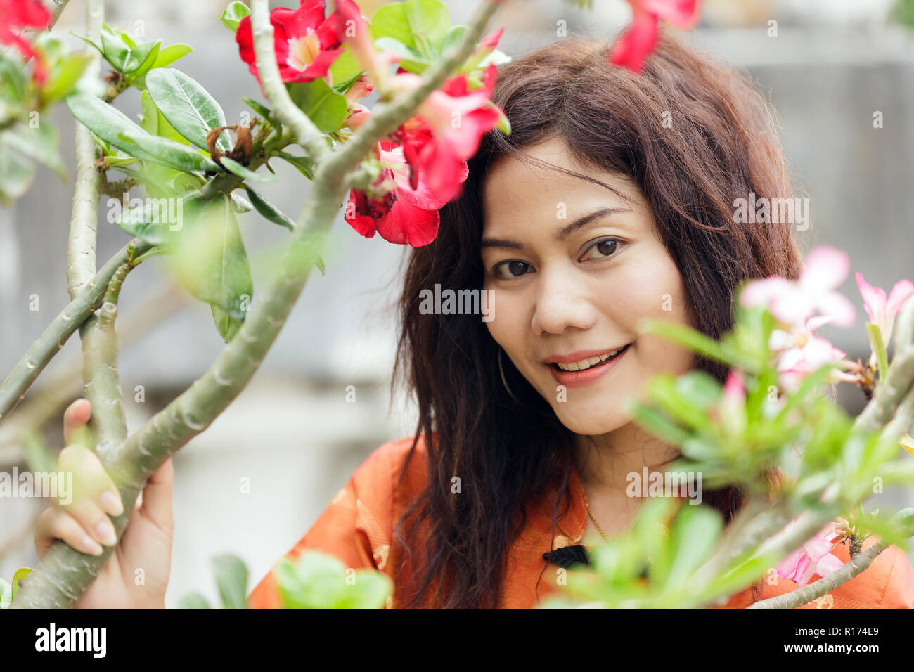 Grazioso Thai lady è in posa tra fiori vivaci in Thailandia Foto Stock