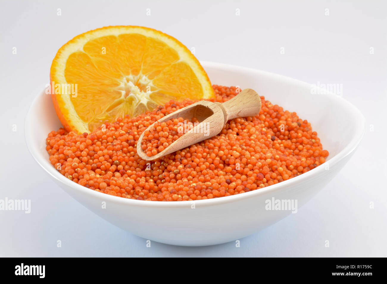 Palloncini di perle di vasca da bagno con il profumo di arancio su uno sfondo bianco, sali da bagno con fetta di colore arancione, Foto Stock