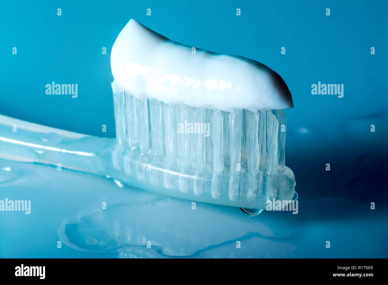 Il dentifricio sullo spazzolino close-up su una tabella con le gocce di acqua su uno sfondo blu scuro Foto Stock