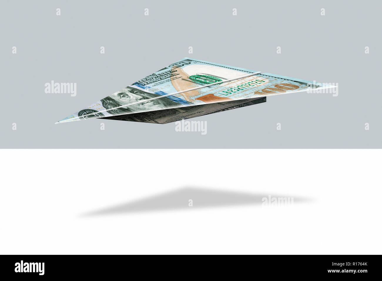 US dollar nota piegata in forma di piano e sfondo grigio Foto Stock