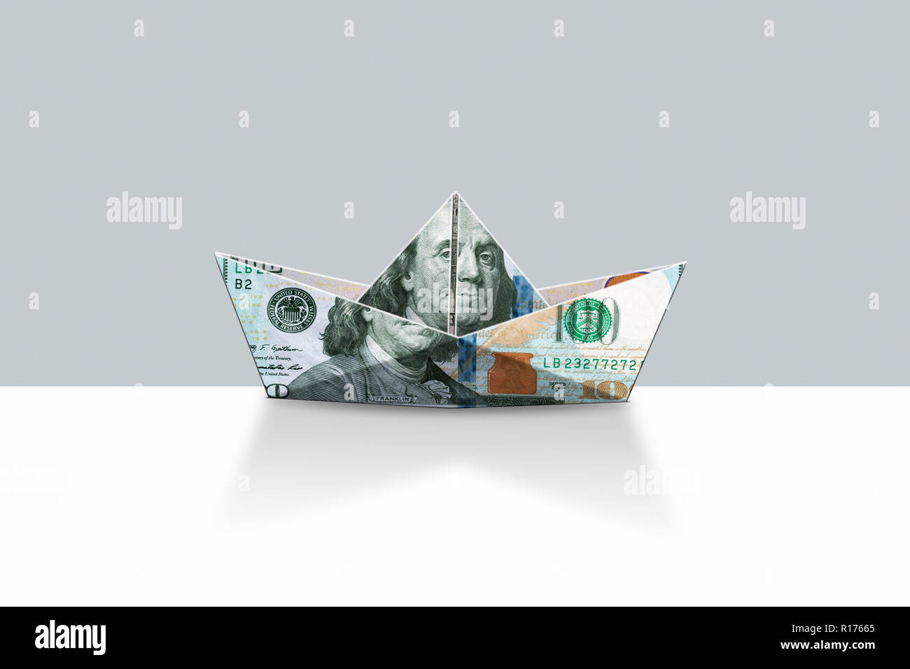 Forma di origami barca da US Dollari e sfondo grigio Foto Stock