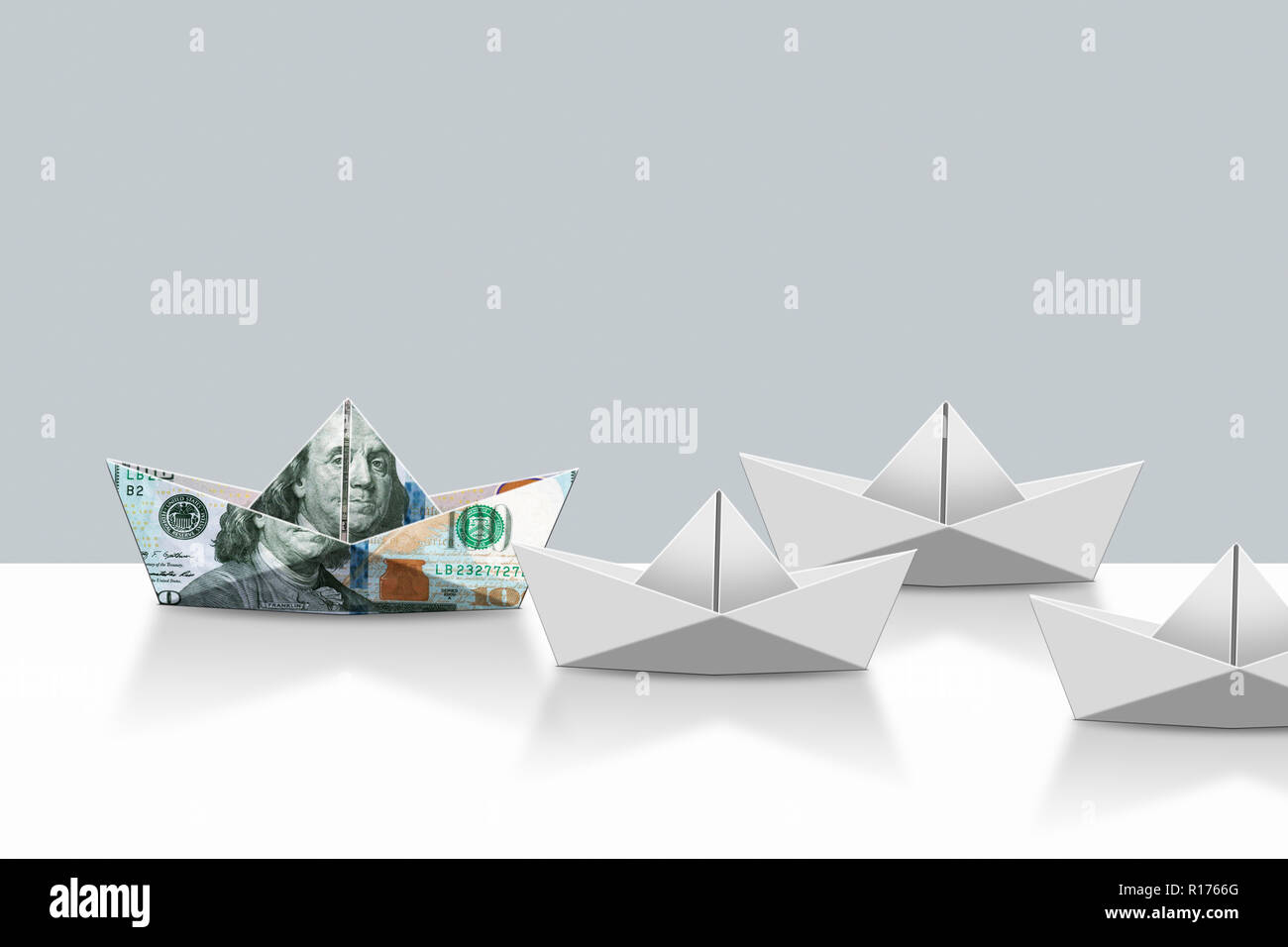 US dollar nota e carta origami barche, uno sfondo grigio Foto Stock