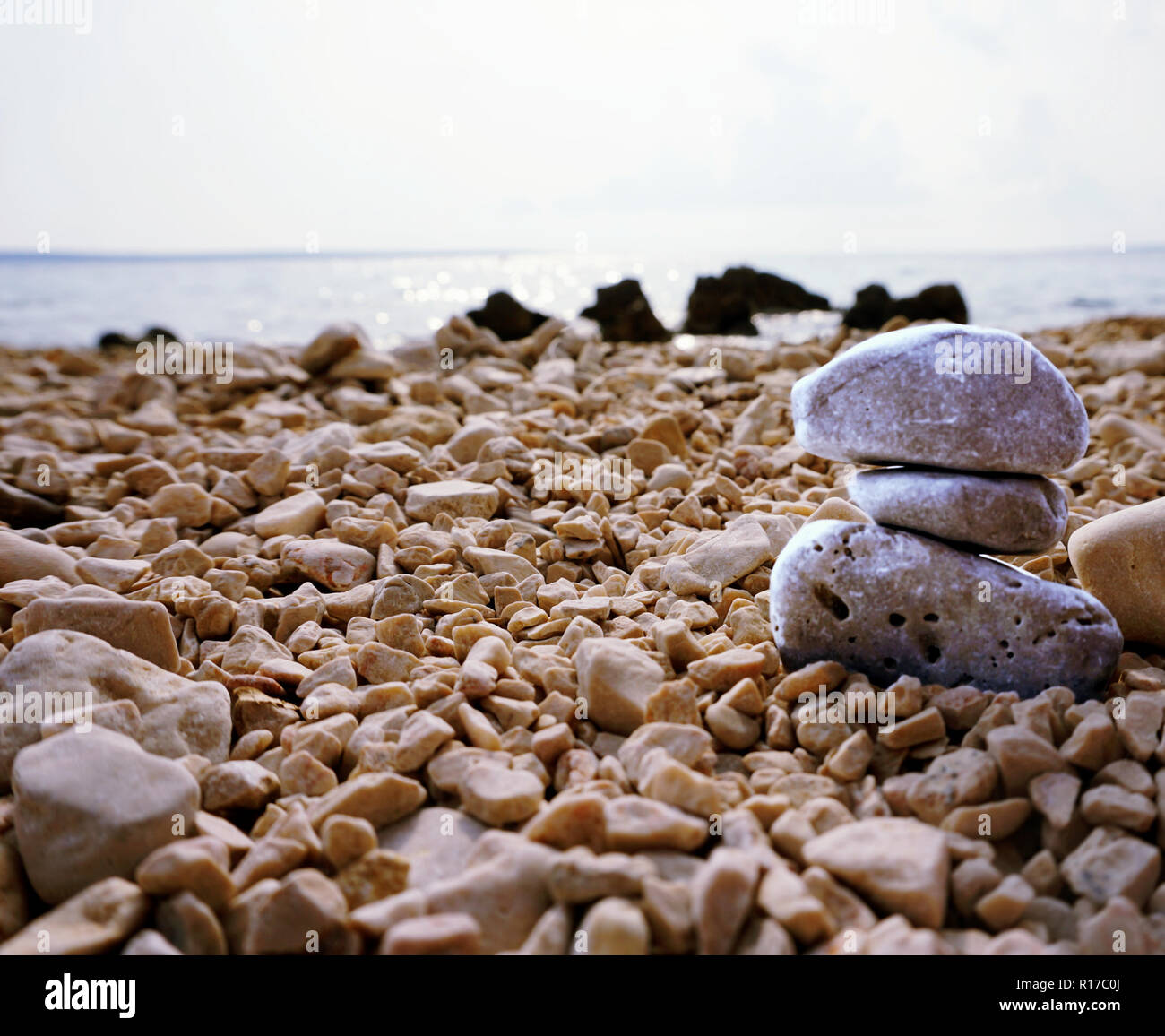 Spiaggia ghiaiosa vista ravvicinata con pietra blu cairn Foto Stock