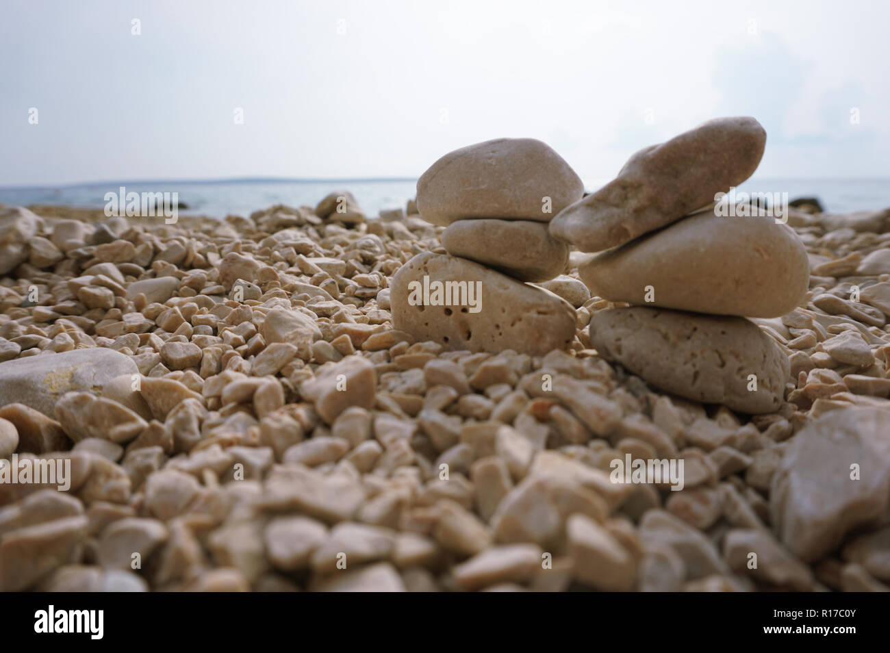 Coppia di la pietra cairn sulla spiaggia di ciottoli in un giorno nuvoloso Foto Stock