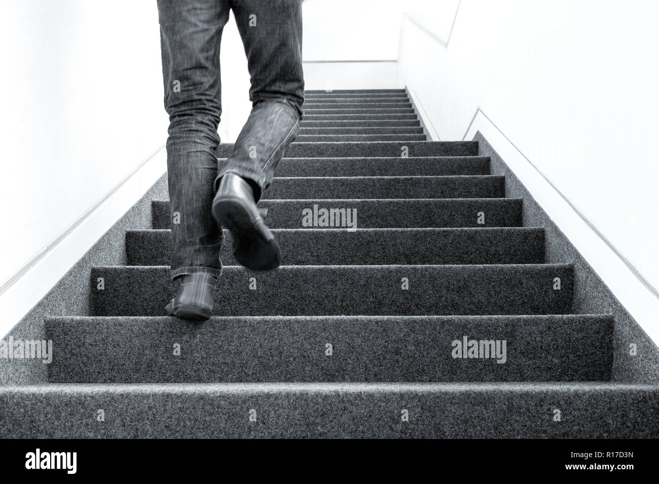 In bianco e nero a basso angolo immagine di un uomo che cammina al piano superiore sulla scala in ambienti interni Foto Stock