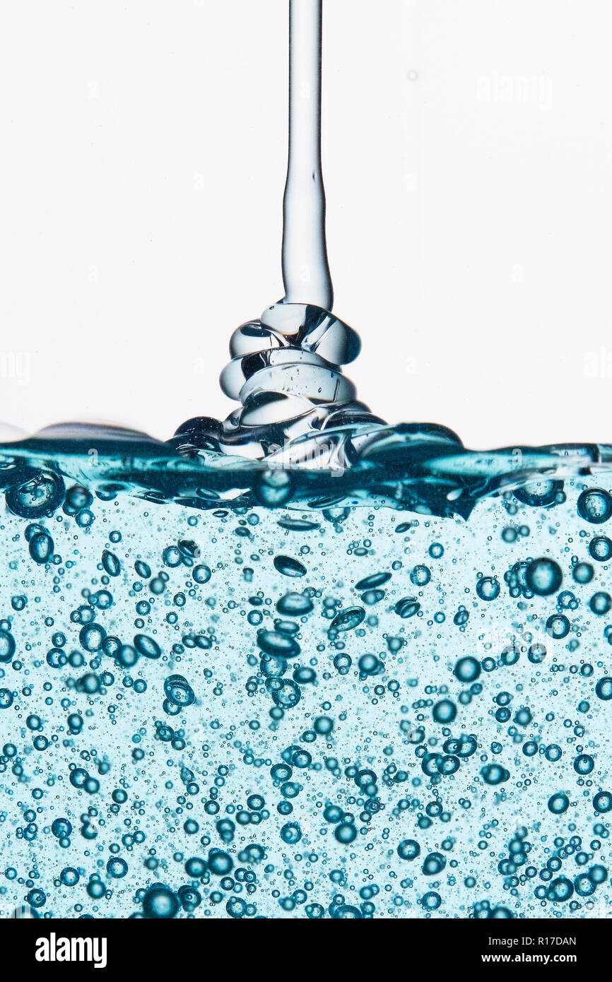Blu trasparente gel con bolle essendo spruzzata contro uno sfondo bianco Foto Stock