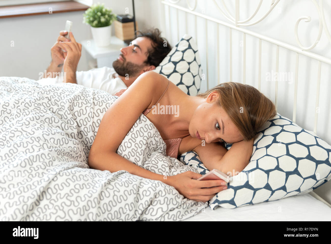 Coppia giovane con gli smartphone nel loro letto. Rapporto cattivo concetto Foto Stock