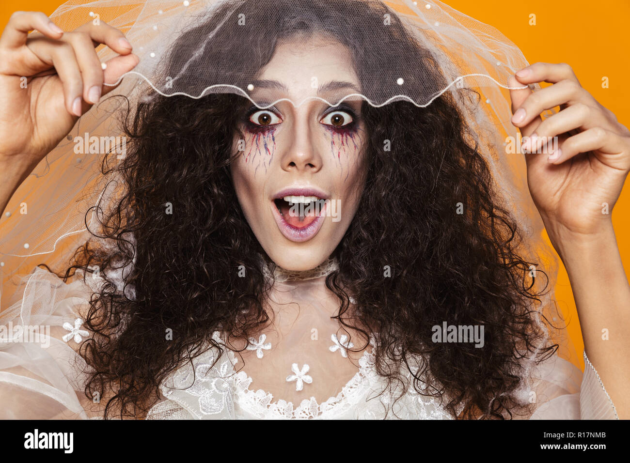 Foto di bella donna zombie di halloween indossando abiti da sposa e trucco  vacanze toccando bianco velo isolate su sfondo giallo Foto stock - Alamy