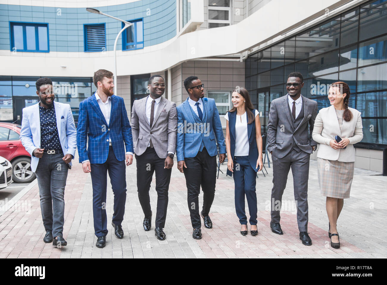 Il successo della società con lavoratori felice. Le donne e gli uomini in abiti aziendali stand con le braccia incrociate contro lo sfondo dei grattacieli. Foto Stock