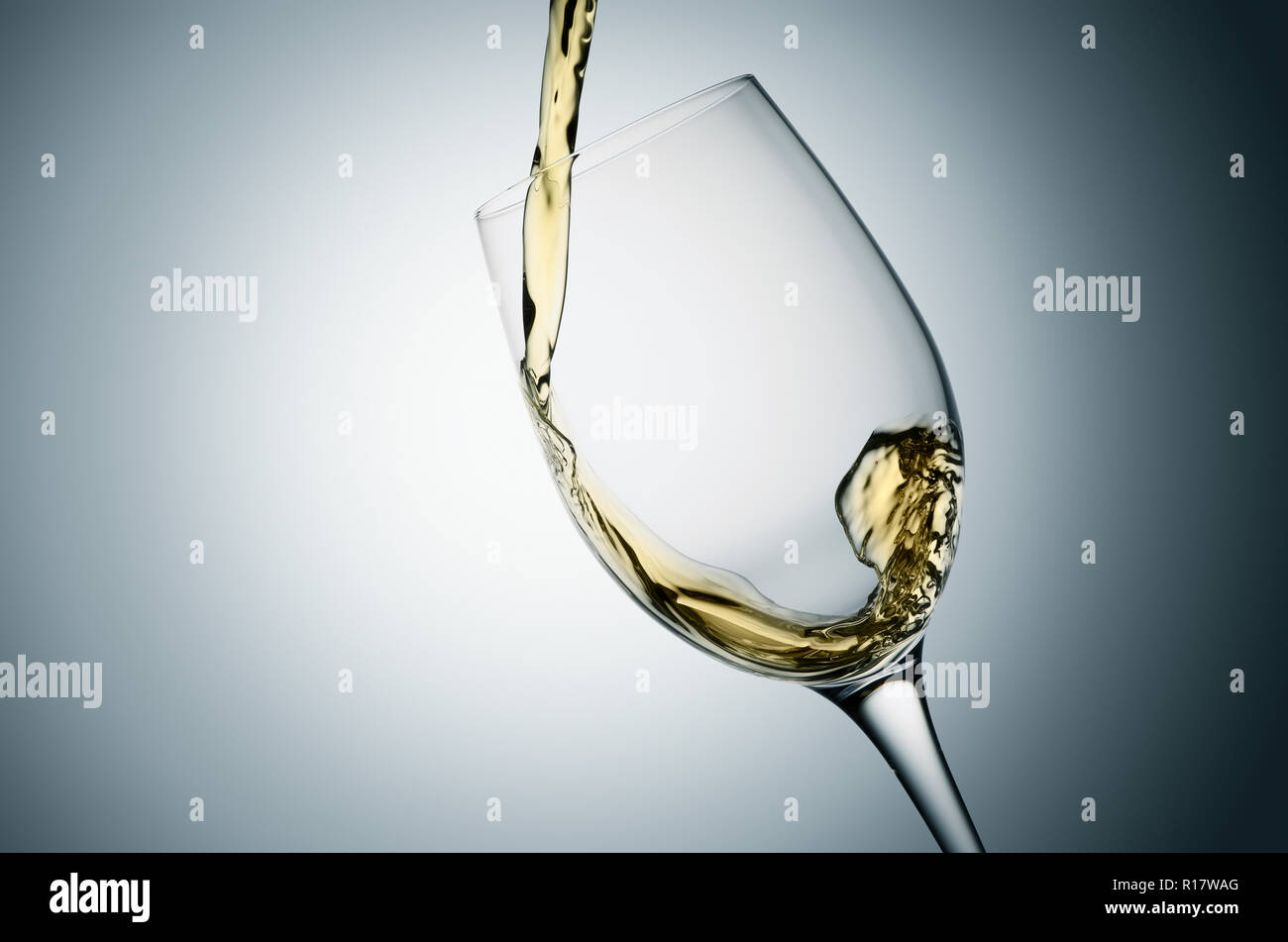 Versare il vino bianco in vetro inclinato, sfondo semplice Foto Stock