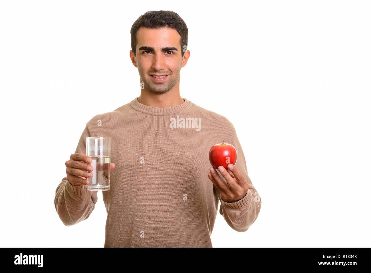 Ritratto di giovane uomo bello tenendo un bicchiere di acqua e Apple Foto Stock