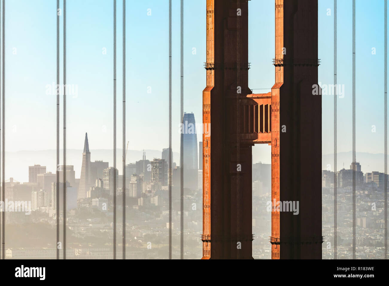 La città di San Francisco, California è osservato attraverso i cavi di sospensione e una torre dell'iconico Golden Gate Bridge su una mattina nebuloso. Foto Stock