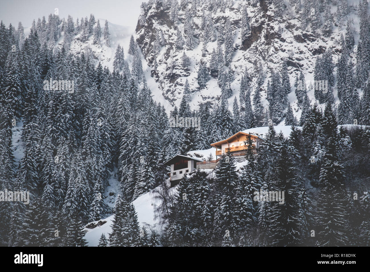 La cabina si illumina la neve valle coperta di abeti misty mountain prima luce alba Foto Stock