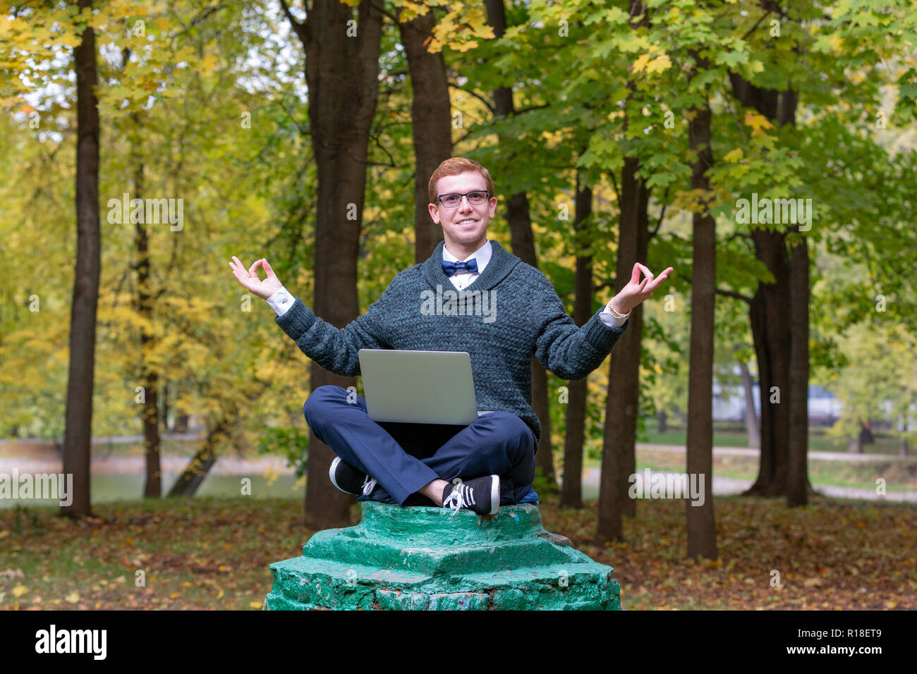 Un uomo su un piedistallo che finge di essere una statua medita nella posizione del loto nel parco. Foto Stock
