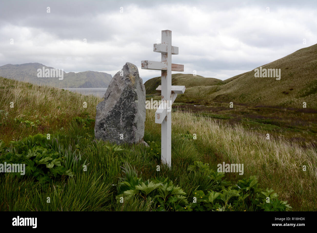 Una chiesa russo-ortodossa croce sulla cima di un grave su un pendio erboso oltre il mare di Bering, Unalaska Isola Arcipelago di Isole Aleutine, Stati Uniti. Foto Stock