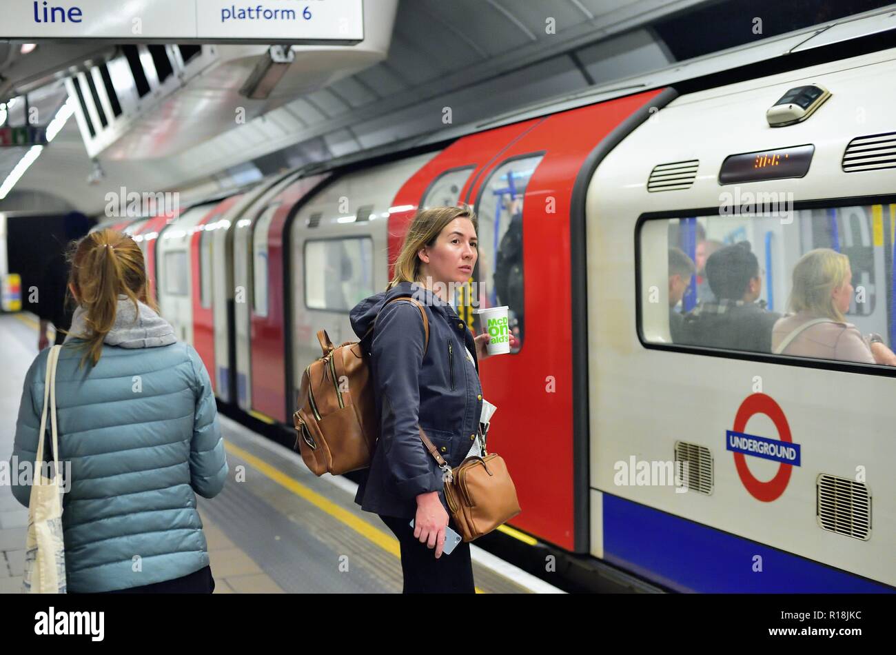 Londra, Inghilterra, Regno Unito. Passeggeri awiting il arriveal di una linea centrale in metropolitana (metropolitana) in treno alla stazione di Oxford Circus. Foto Stock