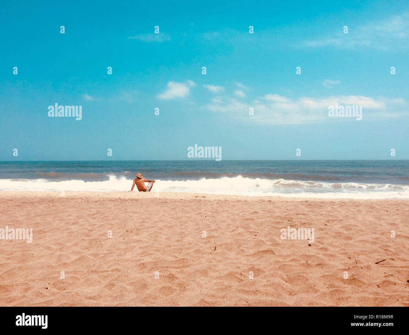 L uomo dal di dietro seduti sulla spiaggia da sola guardando ocean Foto Stock L uomo dal di dietro seduti sulla spiaggia da sola guardando ocean Foto Stock