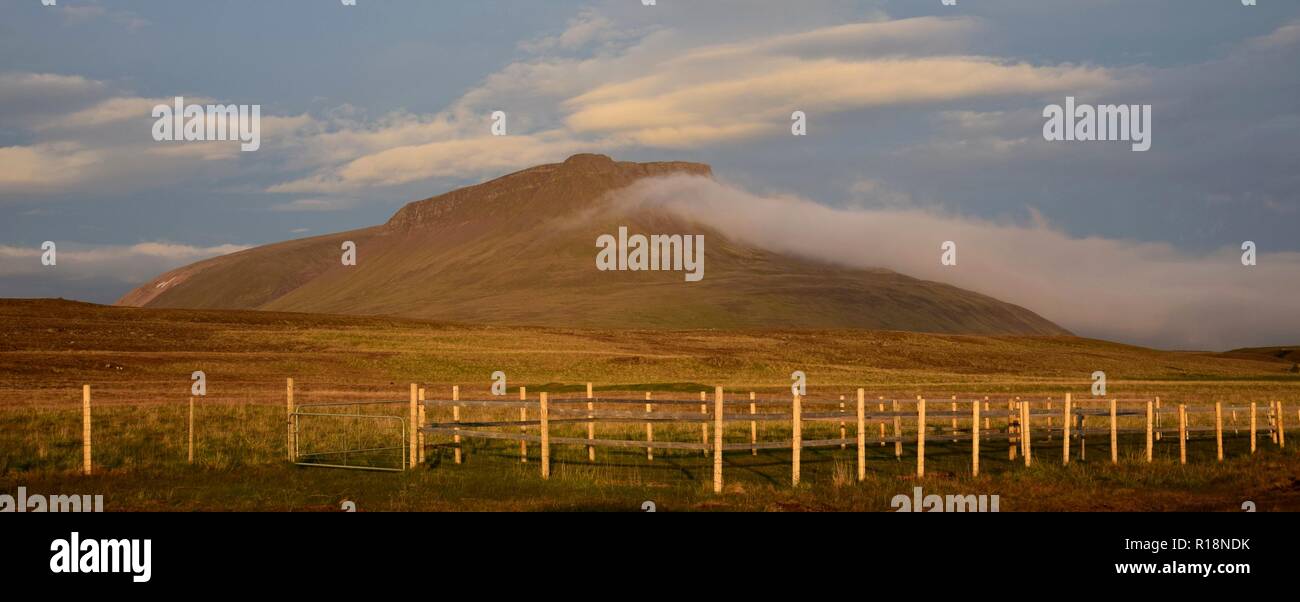 Una notte di mezza estate in Islanda. Una montagna è incandescente nel sole di mezzanotte. Una nuvola in cima alla montagna. Foto Stock