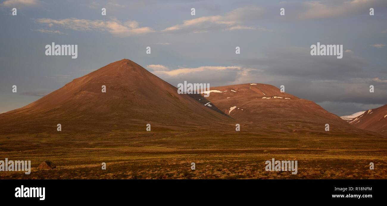 Una notte di mezza estate in Islanda. Una montagna è incandescente nel sole di mezzanotte. Il Svinadalsfjall vicino a Blönduos. Una luce blu del cielo. Foto Stock