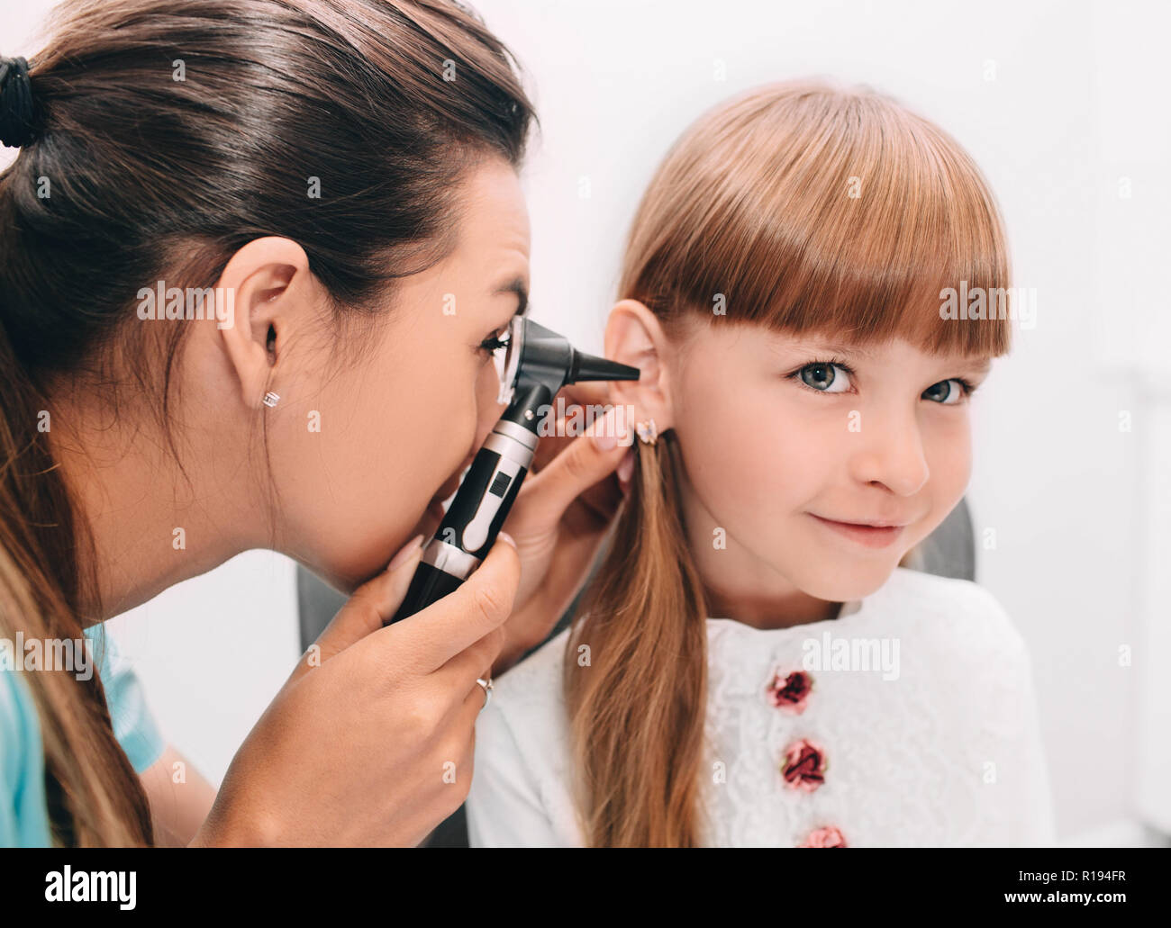 Medico sorridente esaminando bambino orecchio utilizzando otoscopio Foto Stock