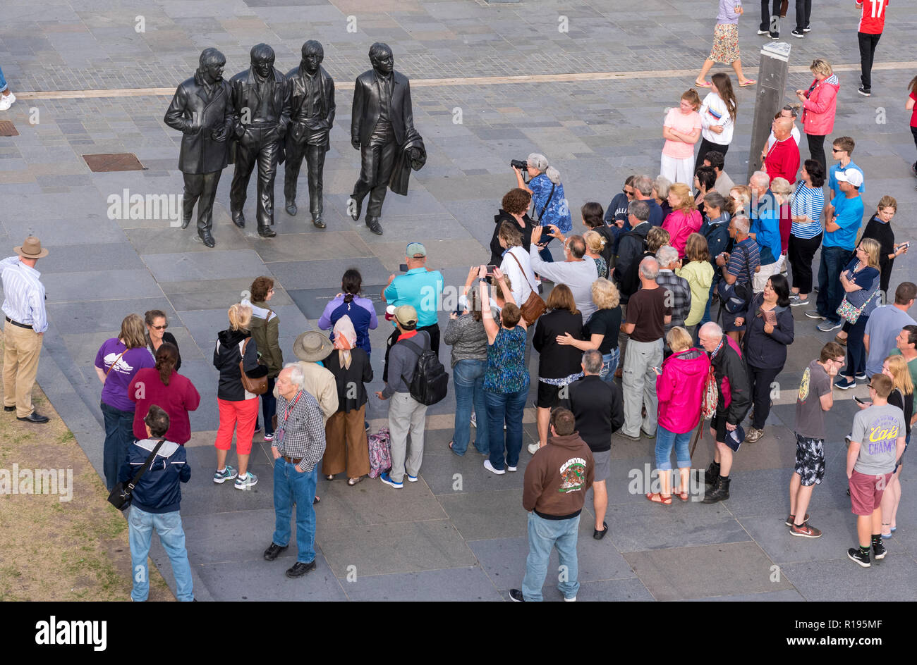 Visite turistiche in Liverpool turisti visitano i Beatles statua su di Liverpool Waterfront al Pier Head. La gigantesca statua in bronzo del Fab Four è un m Foto Stock