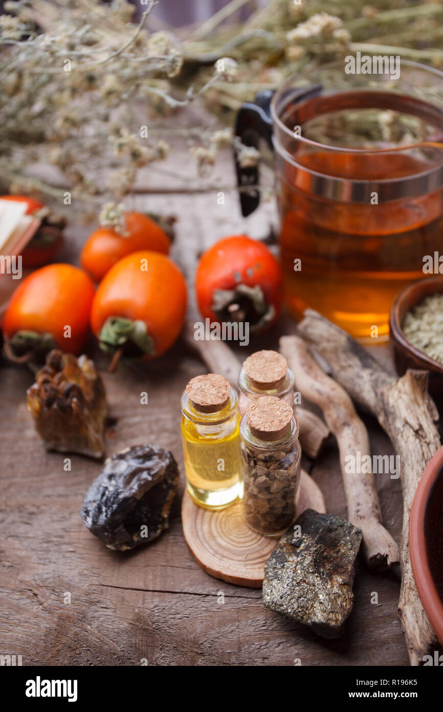 Bottiglie con emulsione, pietre, asciugare le erbe aromatiche e i dettagli in legno. Occulto, esoterico, divinazione e wicca concetto. Mystic, vecchia farmacia e backgr vintage Foto Stock