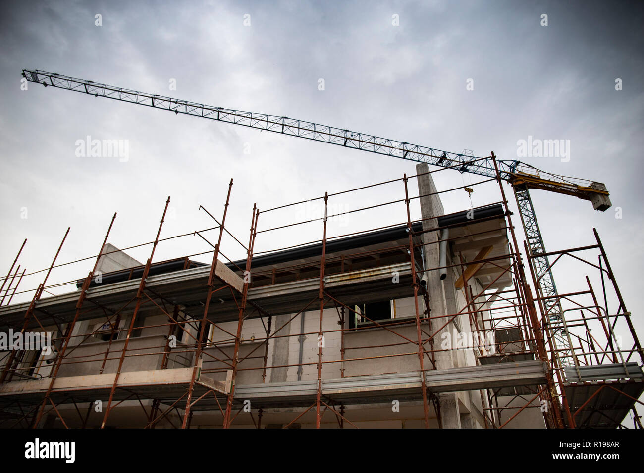 Dettaglio di un edilizia residenziale del sito con i ponteggi e gru a torre, con nuvoloso cielo grigio. Foto Stock