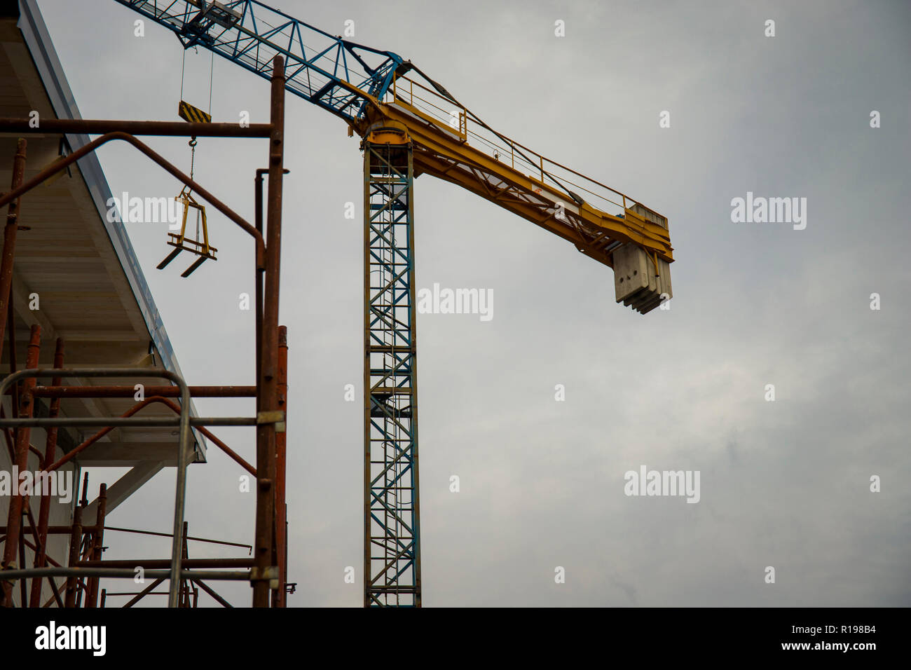 Gru a torre in una costruzione residenziale sito con copyspace su nuvoloso cielo grigio. Foto Stock