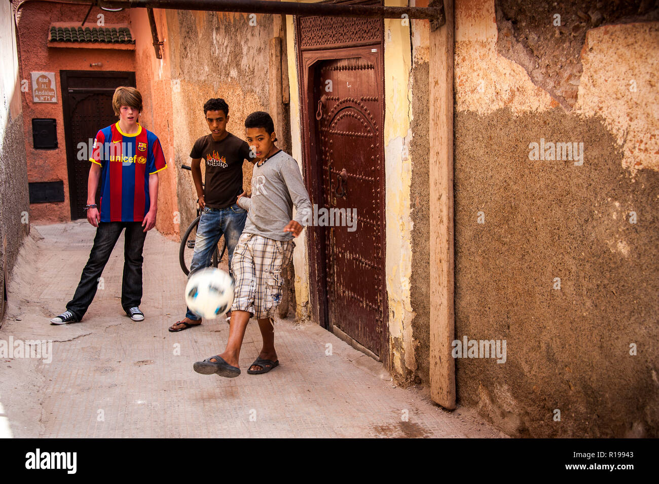 18-04-11. Marrakech, Marocco. Ragazzo inglese giocando a calcio con Morroccan ragazzi in un vicolo della medina. Foto © Simon Grosset / Q Fotografia Foto Stock