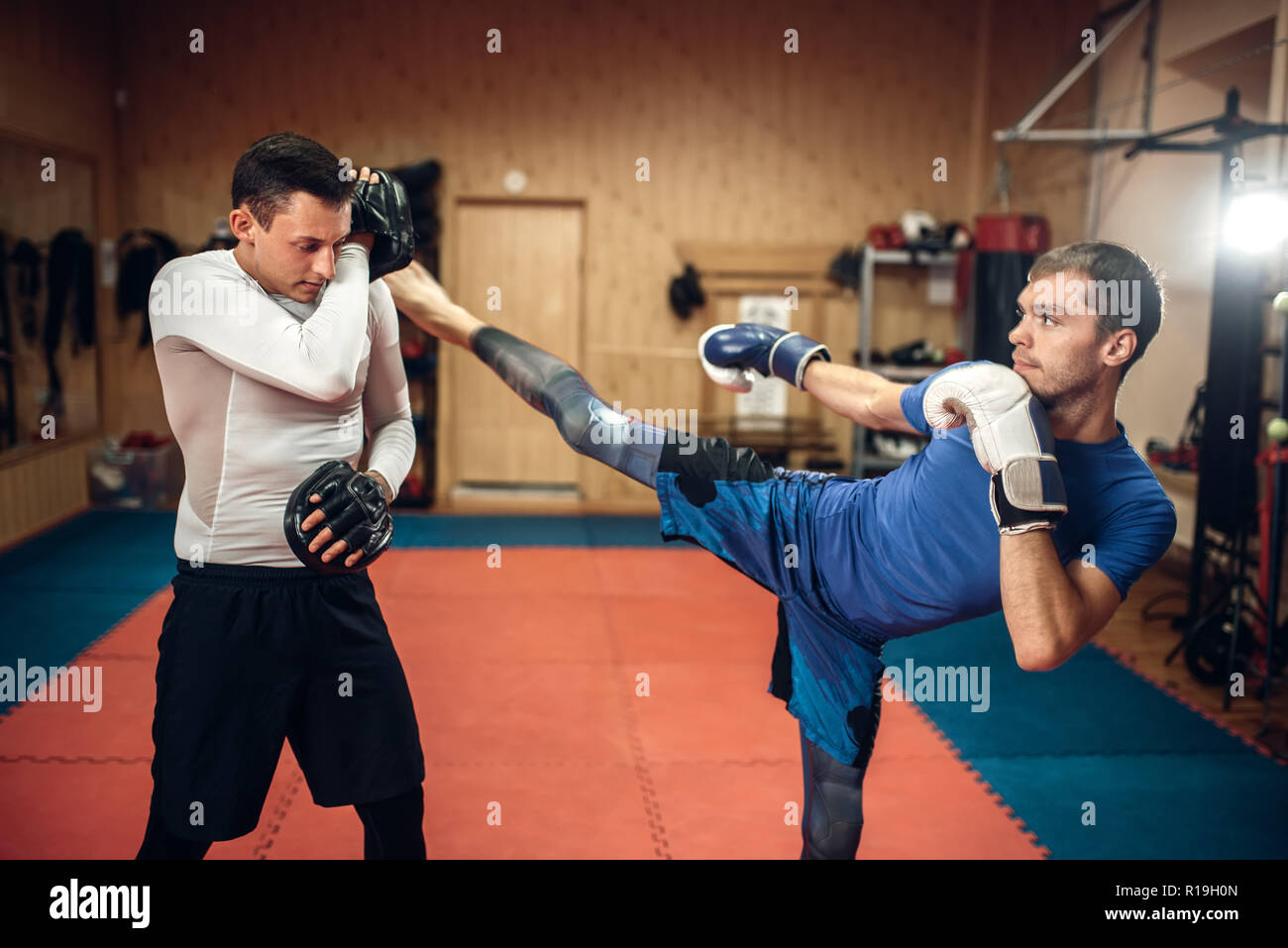 Kickboxer maschio pratica di calci con un personal trainer, allenamento in  palestra. Boxer investe sulla formazione, kickboxing pratica Foto stock -  Alamy