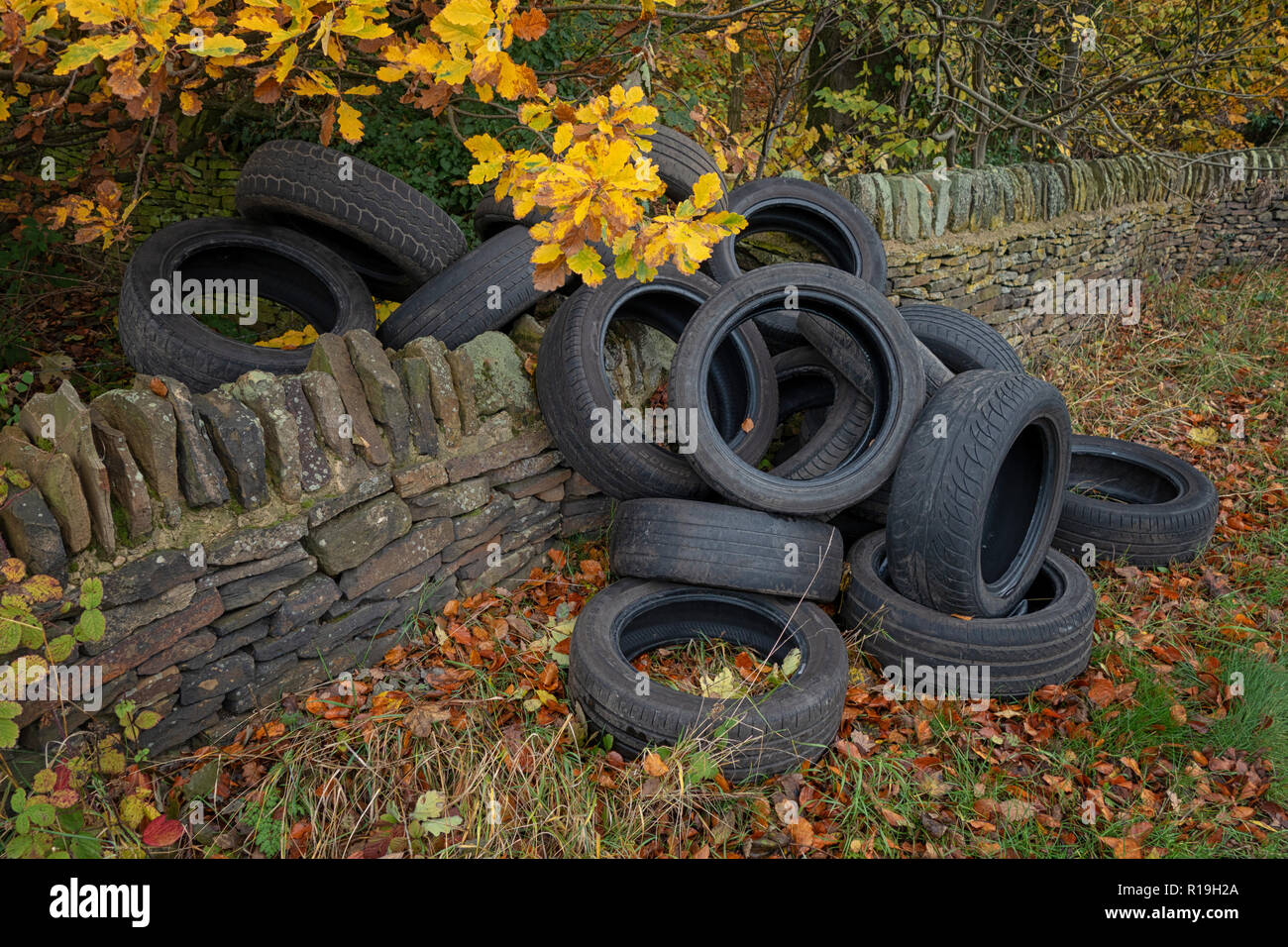 Un mucchio di auto usate di pneumatici oggetto di dumping sul lato di un grazioso vicolo del paese in collina eremita, Wortley, Sheffield, Regno Unito Foto Stock