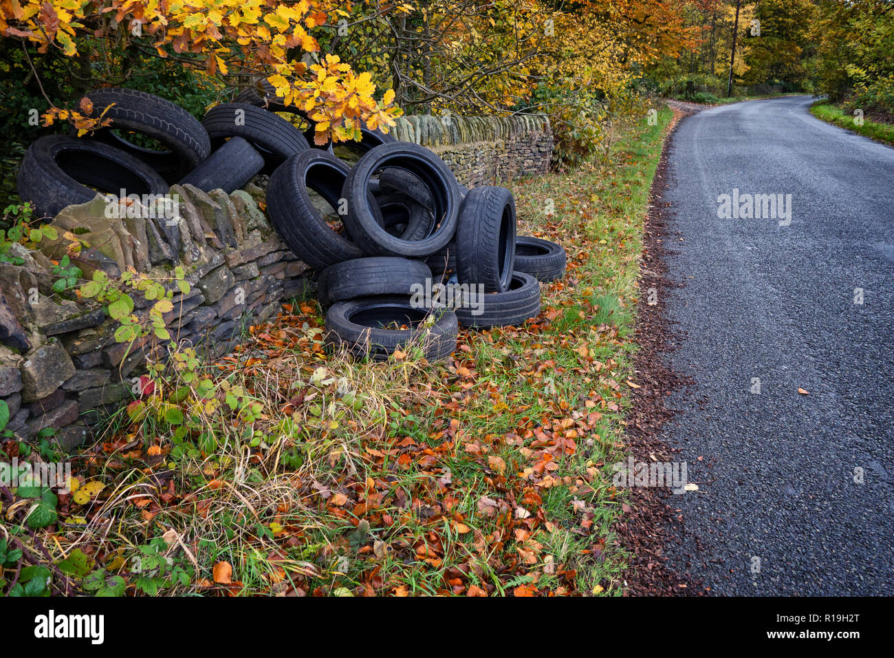 Un mucchio di auto usate di pneumatici oggetto di dumping sul lato di un grazioso vicolo del paese in collina eremita, Wortley, Sheffield, Regno Unito Foto Stock