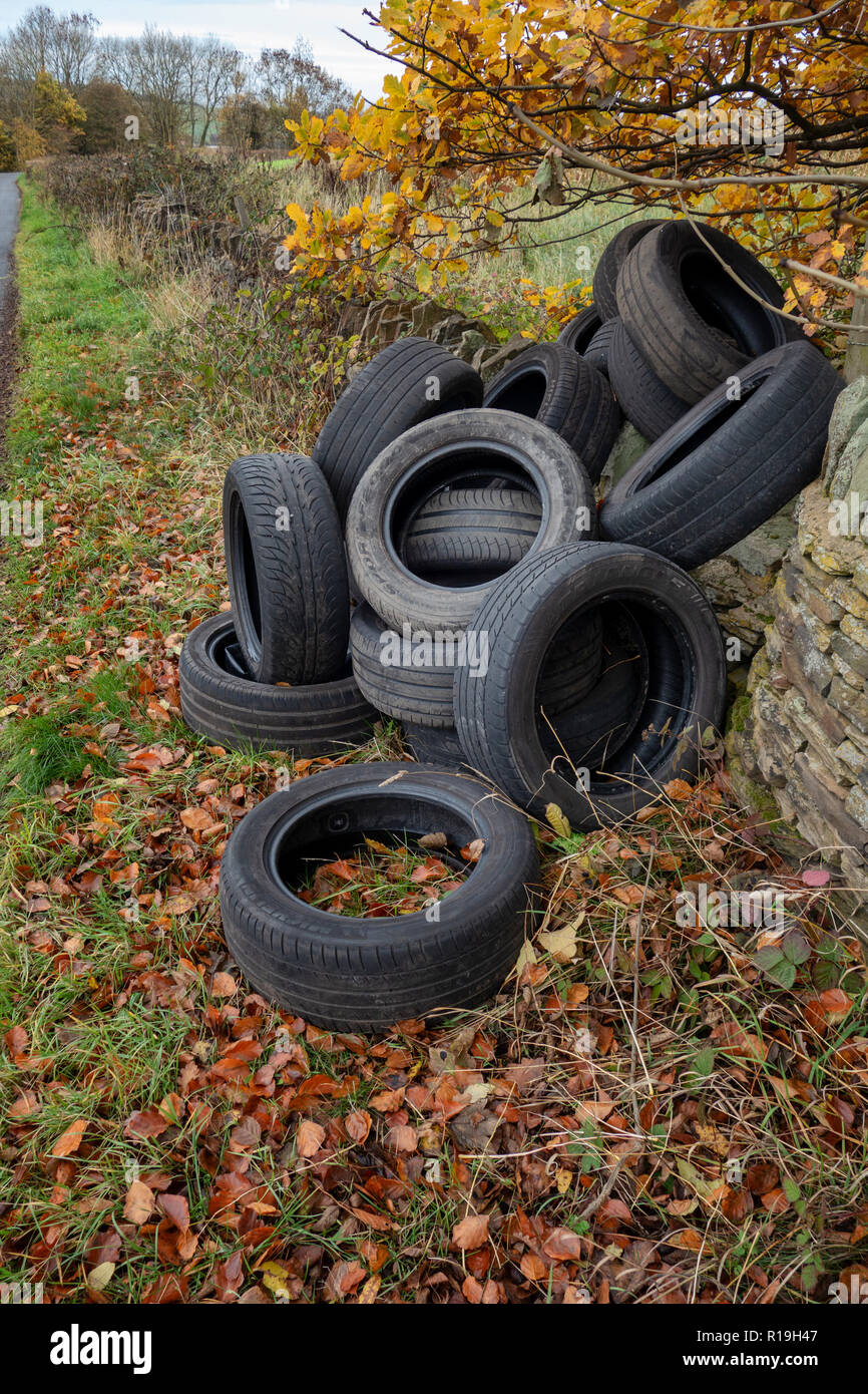 Un mucchio di auto usate di pneumatici oggetto di dumping sul lato di un grazioso vicolo del paese in collina eremita, Wortley, Sheffield, Regno Unito Foto Stock