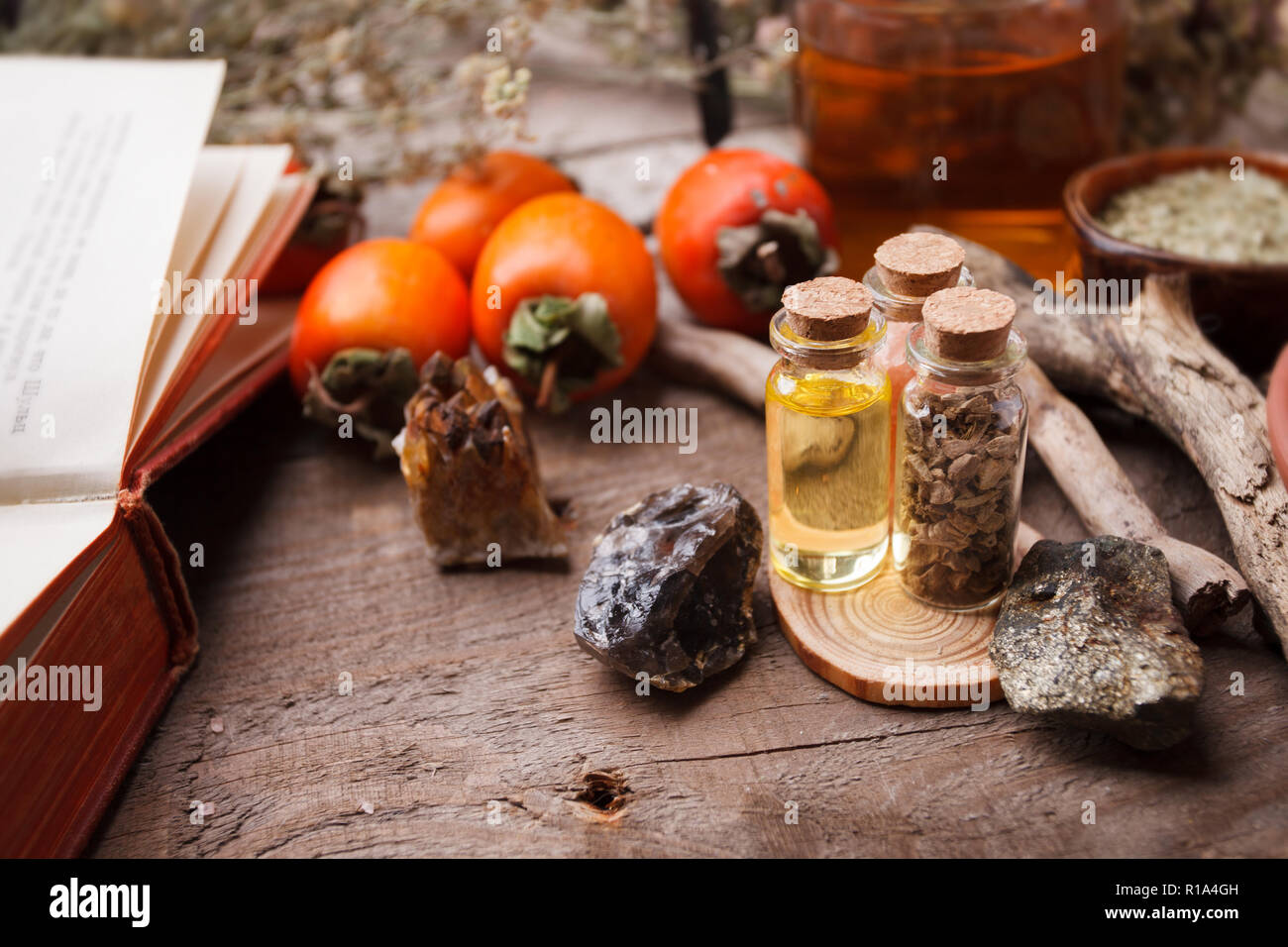 Set di bottiglie, assortimento di secca erbe sane, vecchi libri, pietre e strega il trattamento su vintage scrivania in legno. La medicina di erbe. Vista frontale Foto Stock