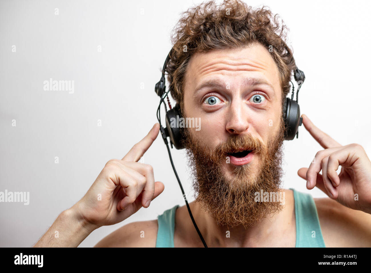 Sorpreso uomo caucasico con capelli ricci e la barba guarda il mio stupore per la fotocamera Foto Stock