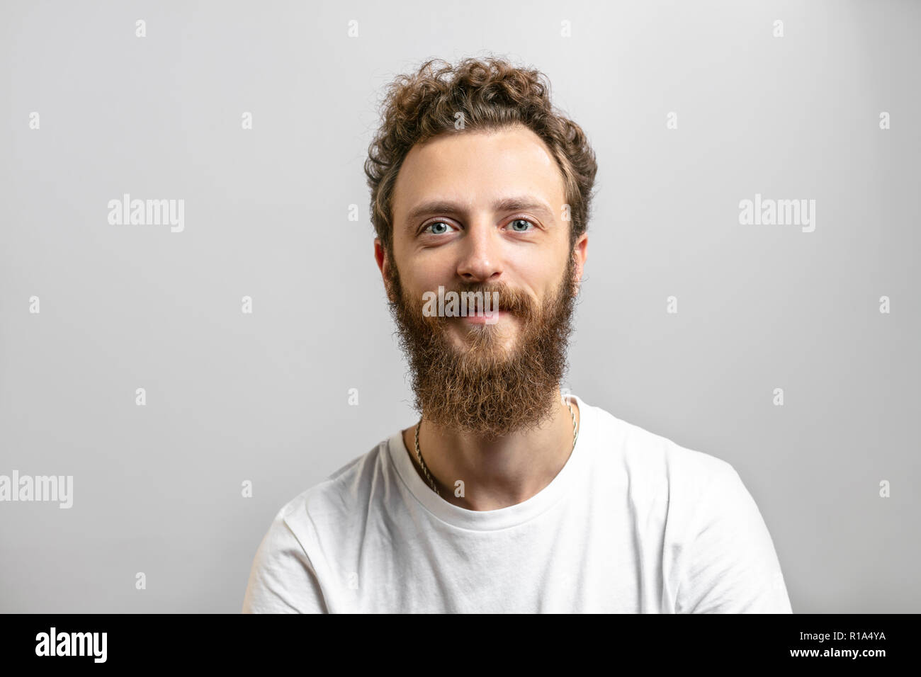 Bello hipster uomo con barba sorridente in telecamera su sfondo bianco. Foto Stock