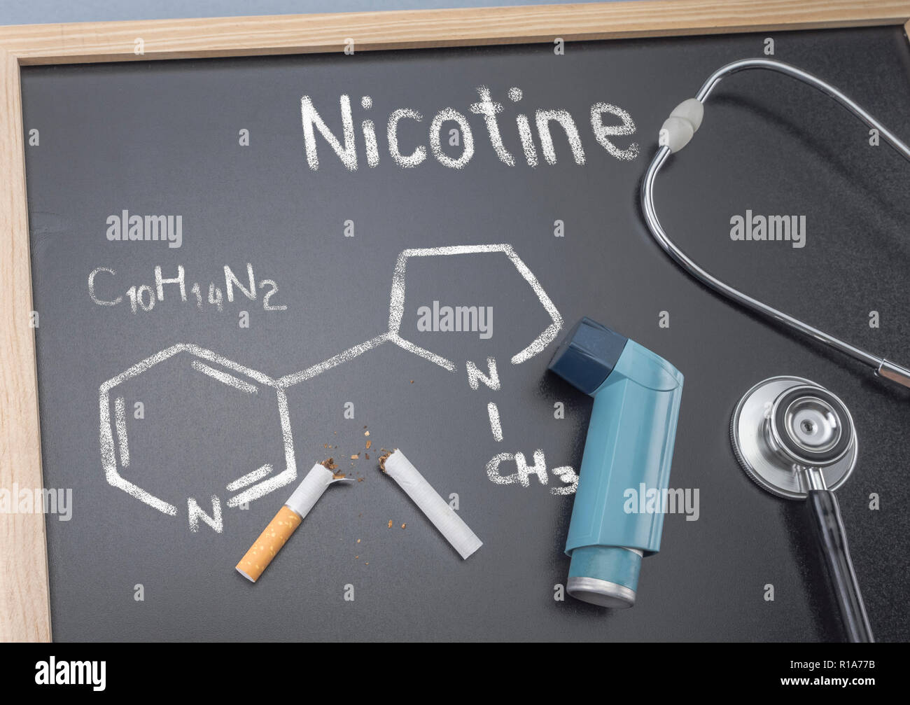 Formula di nicotina chimico scritto e disegnato con un gessetto su una lavagna, accanto a un inalatore e uno stetoscopio, immagine concettuale Foto Stock
